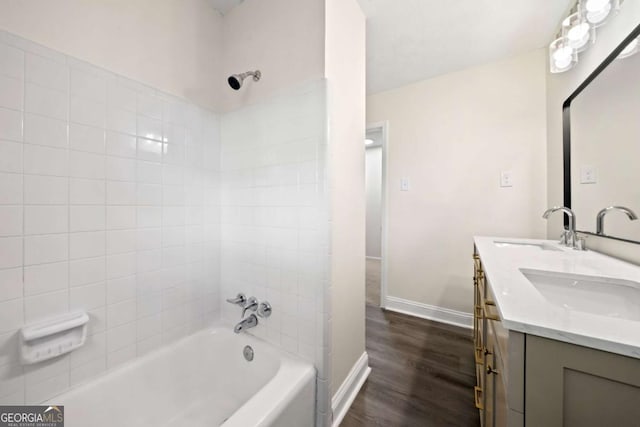 full bath featuring double vanity, baseboards, wood finished floors, tub / shower combination, and a sink