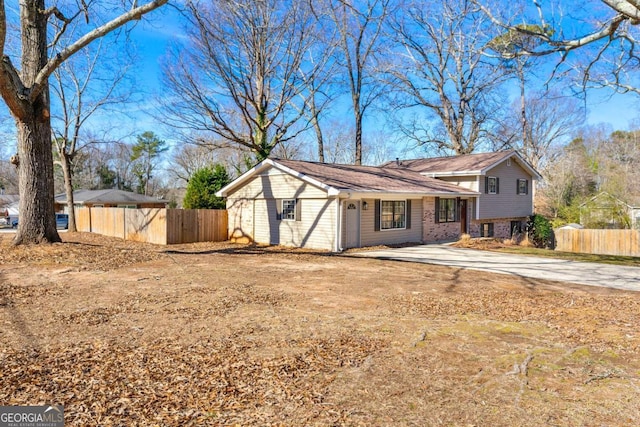 view of front of house with concrete driveway, brick siding, and fence