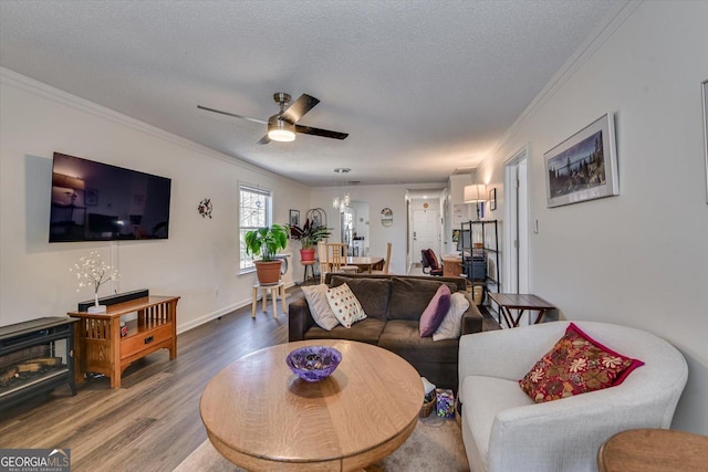 living room with baseboards, a ceiling fan, ornamental molding, wood finished floors, and a textured ceiling