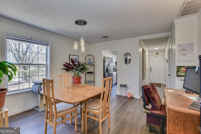 dining area featuring ornamental molding, visible vents, dark wood finished floors, and a textured ceiling