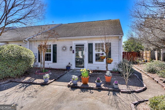 view of front of home with a shingled roof and fence