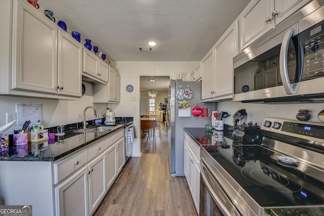 kitchen with light wood finished floors, visible vents, appliances with stainless steel finishes, white cabinetry, and a sink