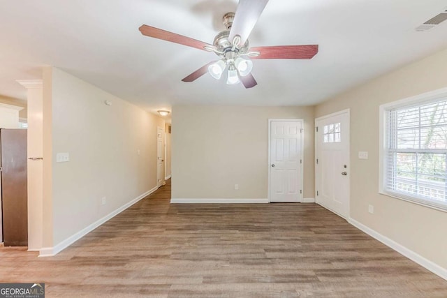 interior space featuring visible vents, a ceiling fan, light wood-style flooring, and baseboards