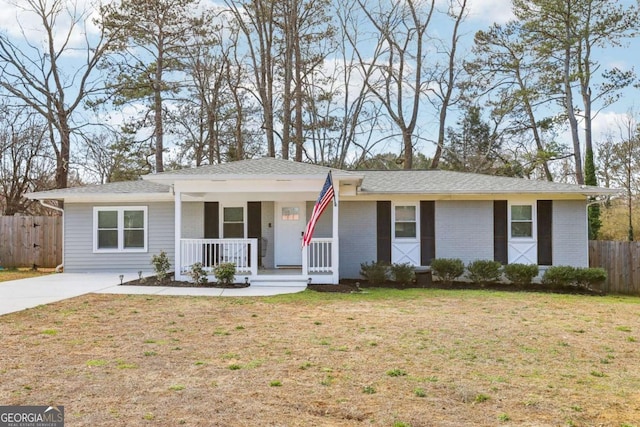 ranch-style house with covered porch, brick siding, a front lawn, and fence