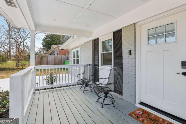 wooden terrace featuring covered porch and visible vents