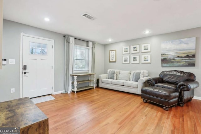 living room with recessed lighting, visible vents, baseboards, and wood finished floors