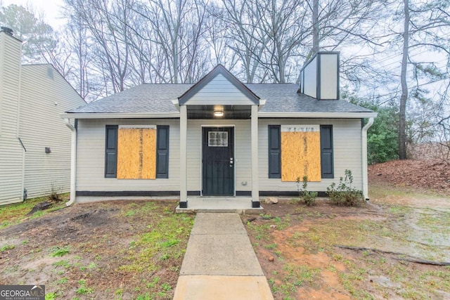 bungalow-style house with a shingled roof and a chimney