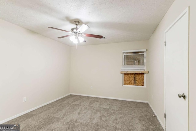 spare room with light carpet, ceiling fan, a textured ceiling, and baseboards