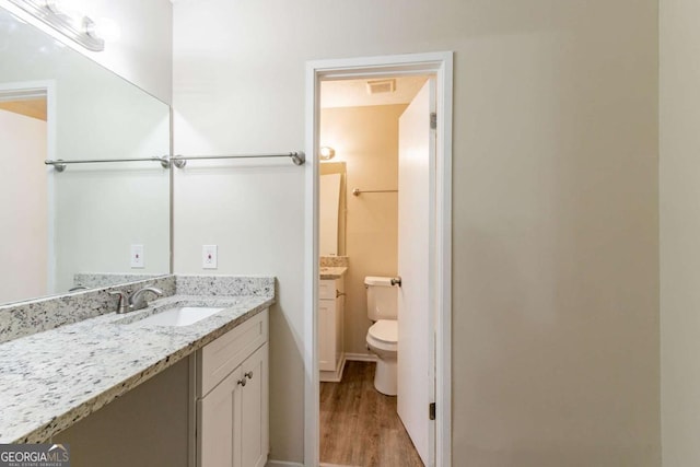 bathroom with visible vents, vanity, toilet, and wood finished floors