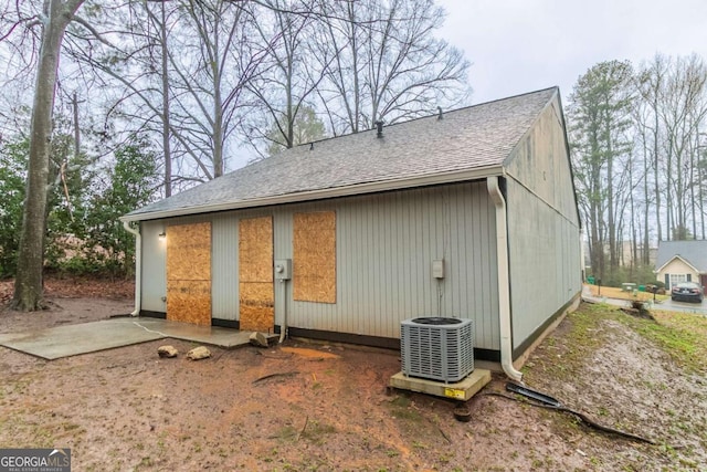 rear view of house with a shingled roof and cooling unit