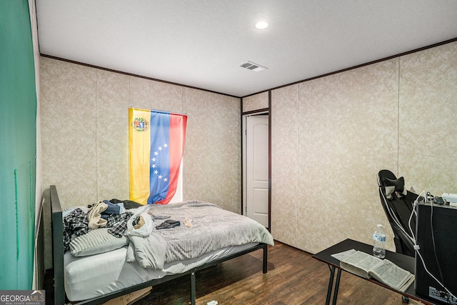 bedroom featuring ornamental molding, wood finished floors, and visible vents