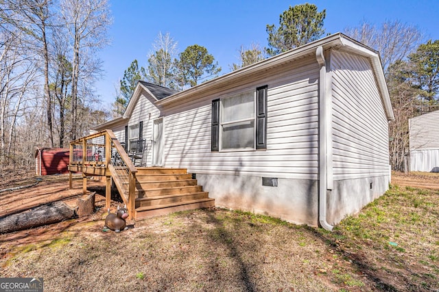 view of property exterior with a deck, stairway, crawl space, and a lawn