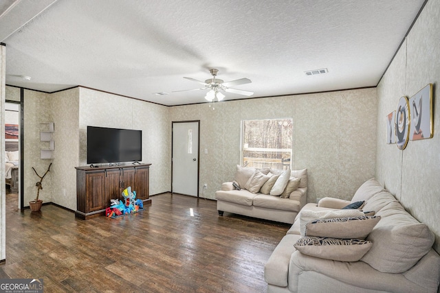 living room featuring ceiling fan, a textured ceiling, visible vents, ornamental molding, and dark wood finished floors