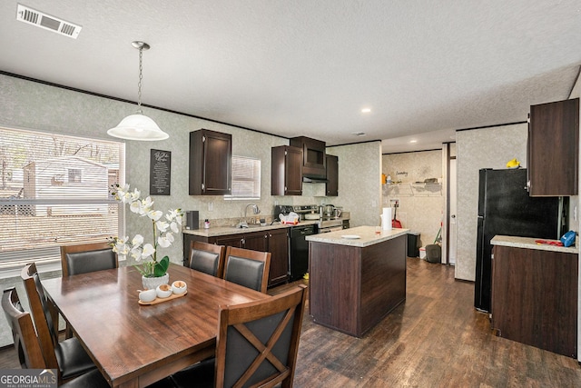 kitchen with a kitchen island, visible vents, light countertops, black appliances, and decorative light fixtures