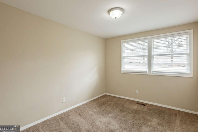 spare room with carpet, visible vents, and baseboards