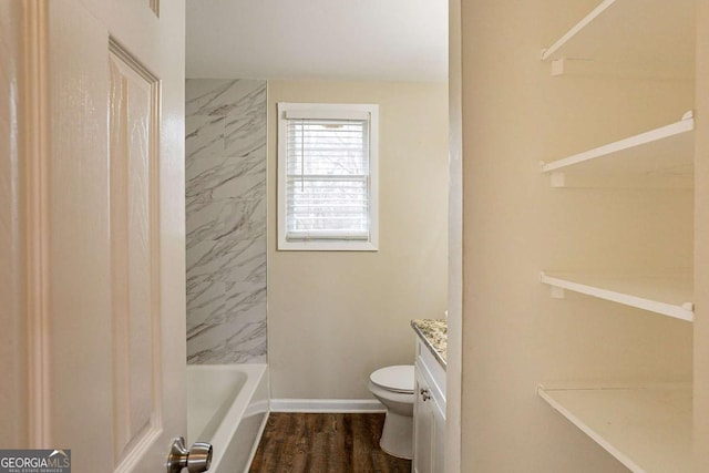 bathroom with baseboards, bathing tub / shower combination, toilet, wood finished floors, and vanity