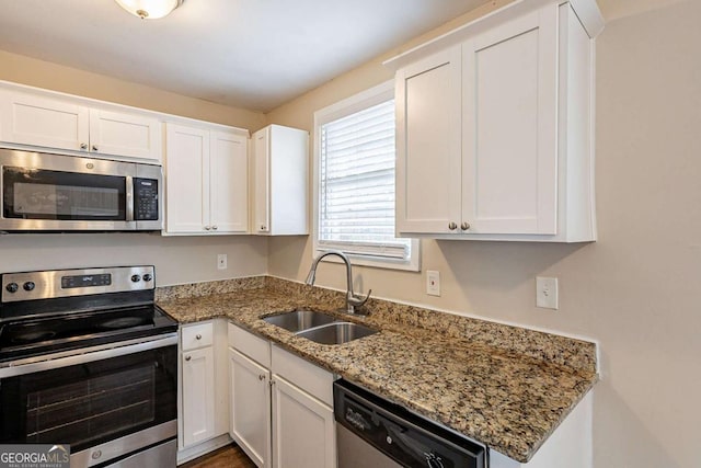 kitchen with stainless steel appliances, a sink, and white cabinets