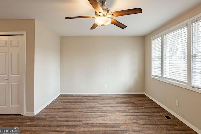 spare room featuring baseboards, visible vents, dark wood finished floors, and a ceiling fan