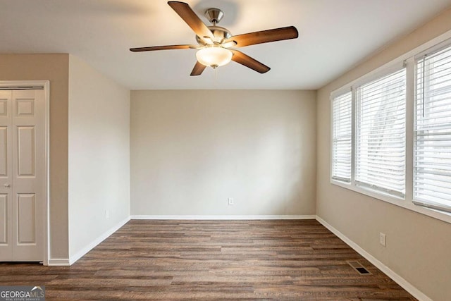 unfurnished room featuring a ceiling fan, baseboards, visible vents, and dark wood-style flooring