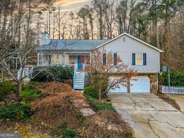 view of front of home featuring a garage, concrete driveway, stone siding, stairs, and a porch