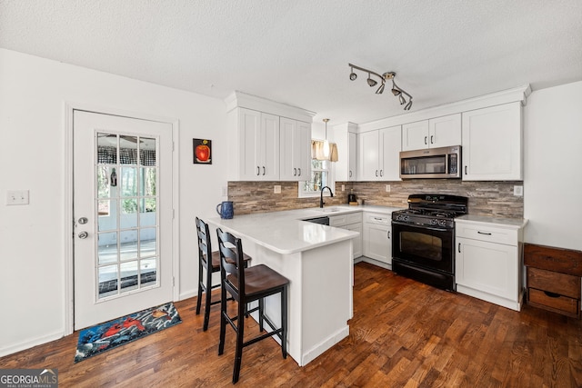 kitchen with white cabinetry, light countertops, stainless steel microwave, gas stove, and pendant lighting