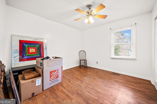 interior space with a ceiling fan, visible vents, baseboards, and wood finished floors