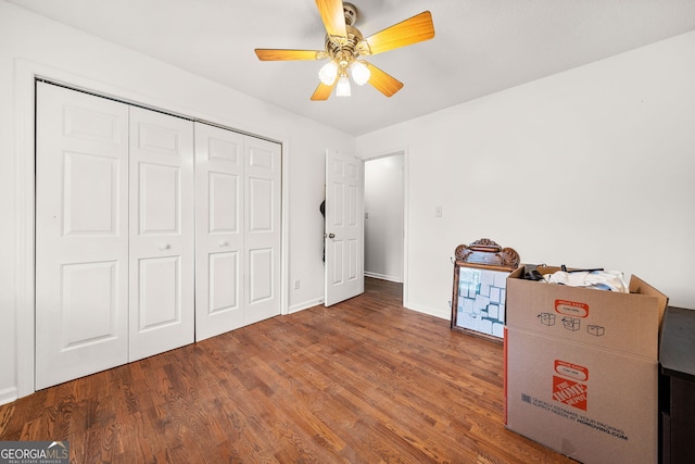 unfurnished bedroom with a closet, wood finished floors, a ceiling fan, and baseboards