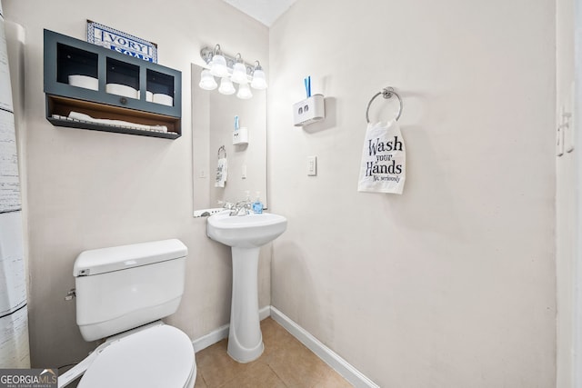 bathroom with toilet, baseboards, a sink, and tile patterned floors