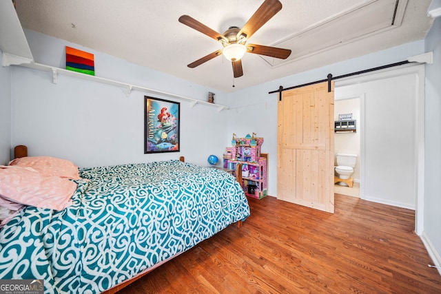 bedroom with baseboards, a barn door, a ceiling fan, and wood finished floors