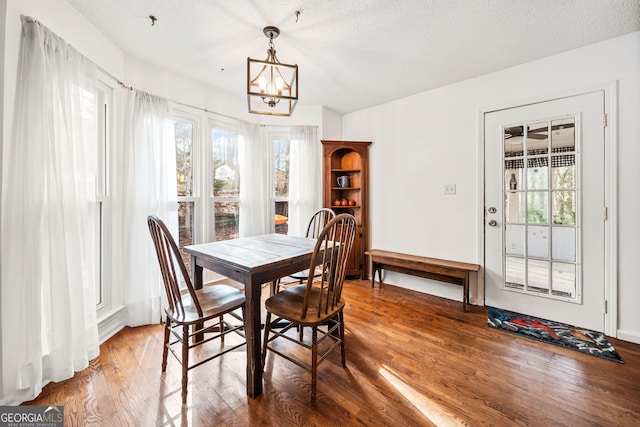 dining area with a chandelier, a textured ceiling, wood finished floors, and a wealth of natural light