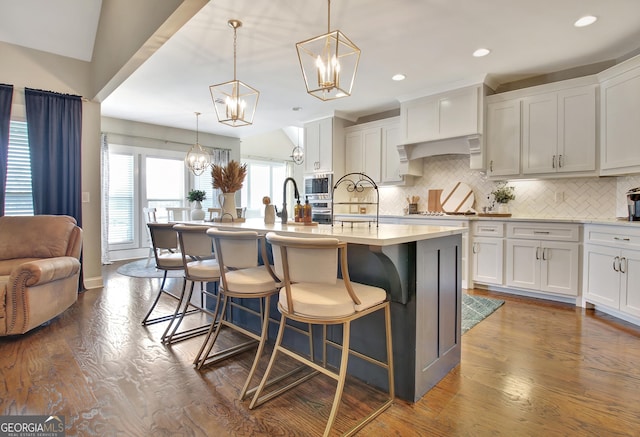 kitchen featuring an island with sink, pendant lighting, and light countertops