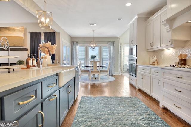 kitchen with appliances with stainless steel finishes, white cabinetry, decorative light fixtures, and an inviting chandelier