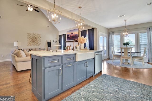 kitchen with open floor plan, stainless steel dishwasher, an island with sink, and pendant lighting