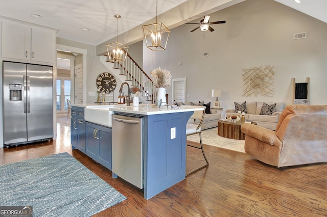 kitchen featuring open floor plan, light countertops, appliances with stainless steel finishes, and an island with sink