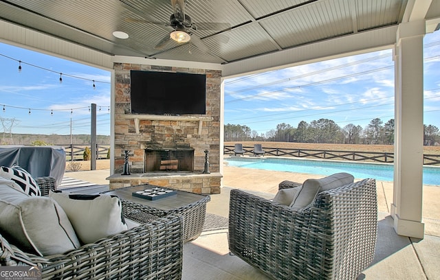 view of patio / terrace with ceiling fan, an outdoor stone fireplace, and a fenced in pool