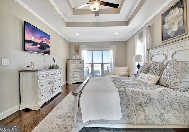 bedroom with ornamental molding, a raised ceiling, and dark wood-style flooring