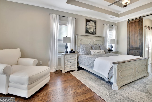 bedroom featuring crown molding, dark wood finished floors, a raised ceiling, visible vents, and a barn door