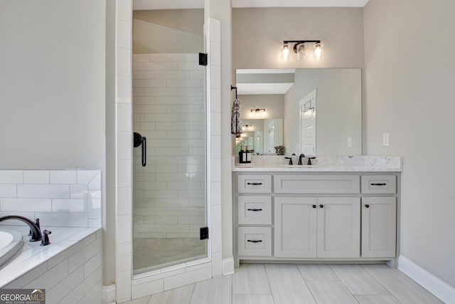 bathroom featuring a shower stall, baseboards, a bath, and vanity