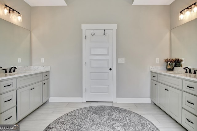 bathroom with baseboards, two vanities, and a sink