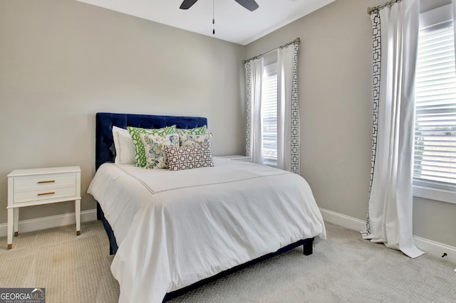 bedroom featuring light colored carpet, baseboards, and multiple windows