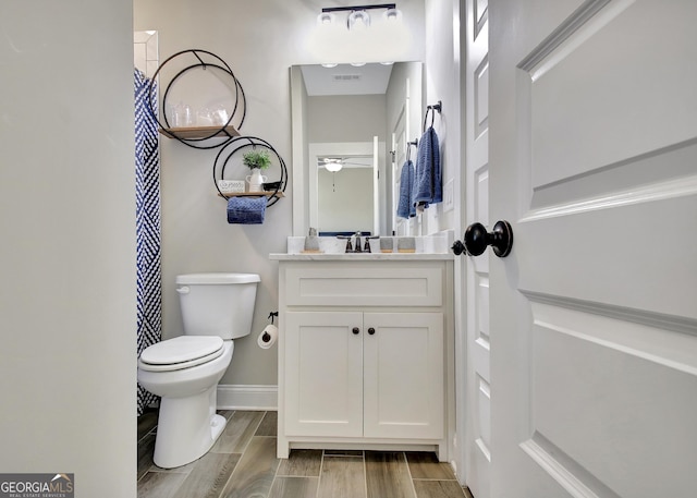 bathroom with toilet, a ceiling fan, wood tiled floor, vanity, and baseboards