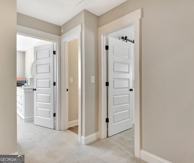 corridor featuring baseboards and light colored carpet