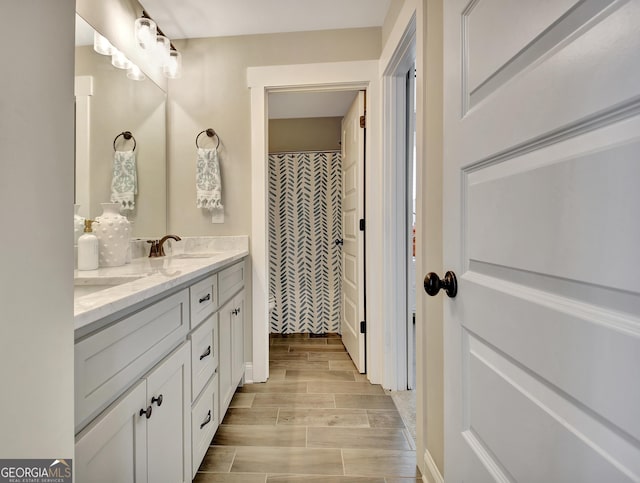 bathroom featuring wood tiled floor, a sink, and double vanity