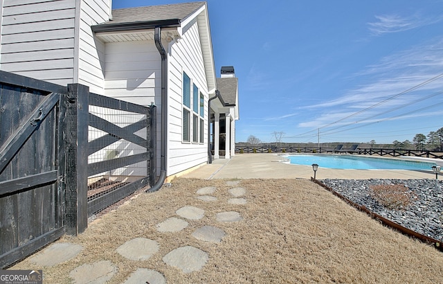 exterior space with a shingled roof, a patio, a community pool, and fence