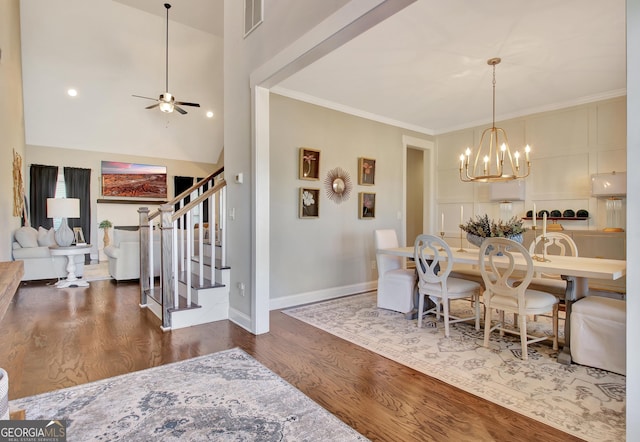 dining room with stairway, dark wood finished floors, crown molding, and ceiling fan with notable chandelier