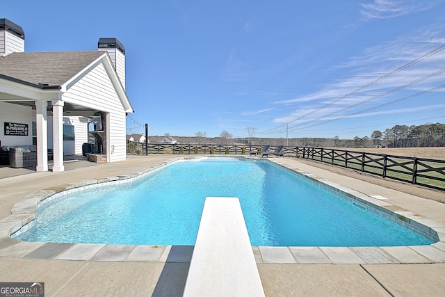 view of pool with a fenced in pool, a diving board, fence, and a patio