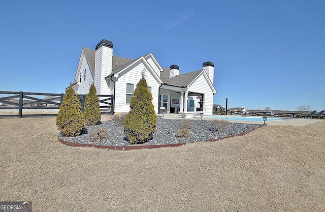 view of side of home featuring fence and a chimney