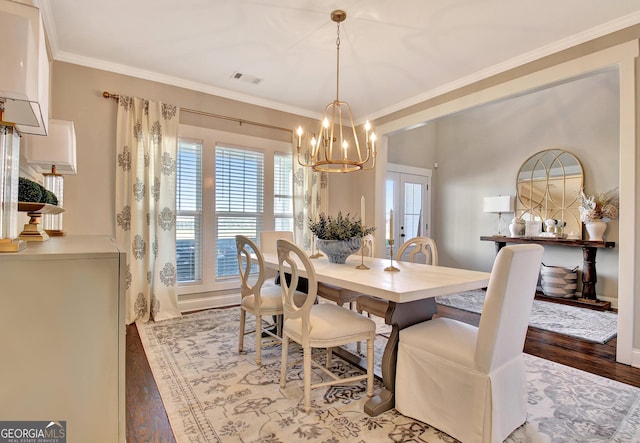 dining room with french doors, a notable chandelier, visible vents, ornamental molding, and wood finished floors