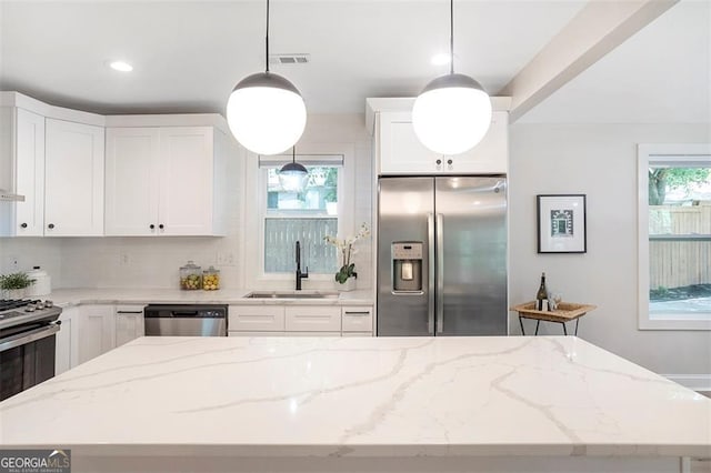 kitchen with a center island, stainless steel appliances, white cabinetry, pendant lighting, and a sink