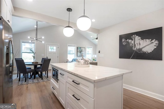 kitchen featuring a kitchen island, stainless steel fridge, white cabinetry, and hanging light fixtures